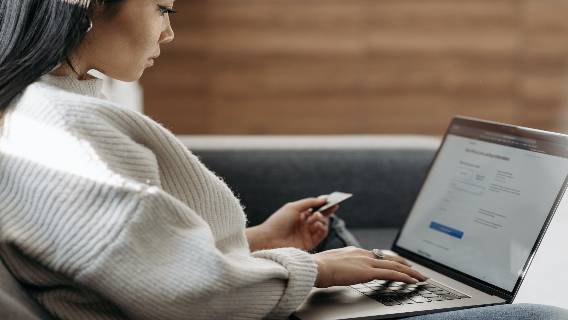 Woman entering her card information onto a website using her laptop